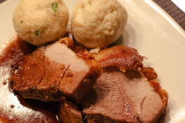 schweinebraten mit knödel auf dem teller