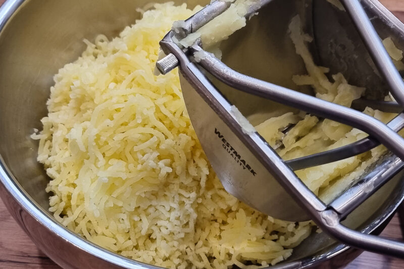 Kartoffel durch die Presse drücken für das Kartoffelpüree