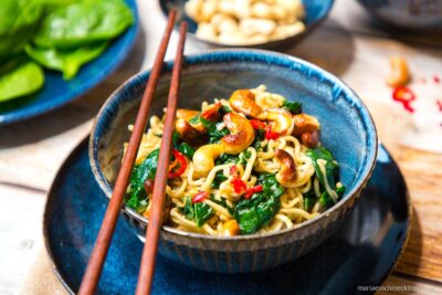 Mie Nudeln mit Spinat und Cashewkernen in einer Schale mit Stäbchen