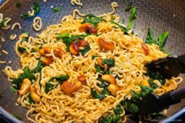 Mie Nudeln mit Spinat und Cashewkernen in der Pfanne zubereitet