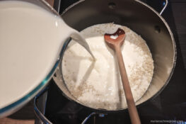 Milch in den Topf mit dem Milchreis gießen