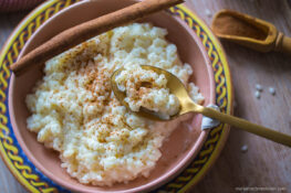 Omas Milchreis in der Schüssel mit Löffel und Zimtstange