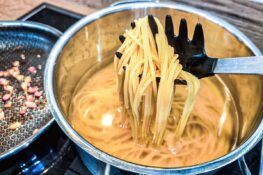 Nudeln tropfnass in die Pfanne zum Speck geben