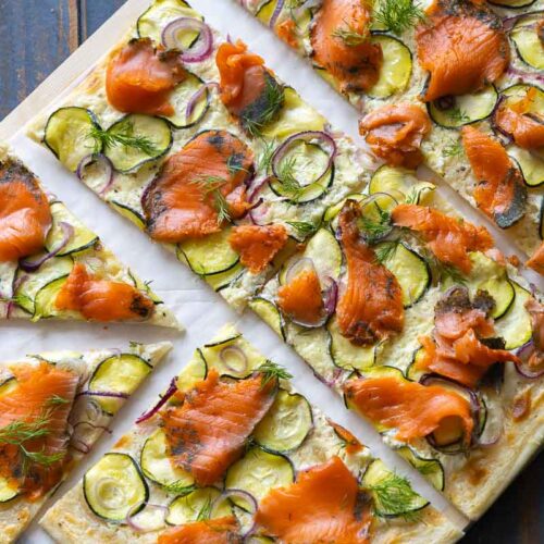 Flammkuchen mit Räucherlachs und Zucchini in stücke geschnitten