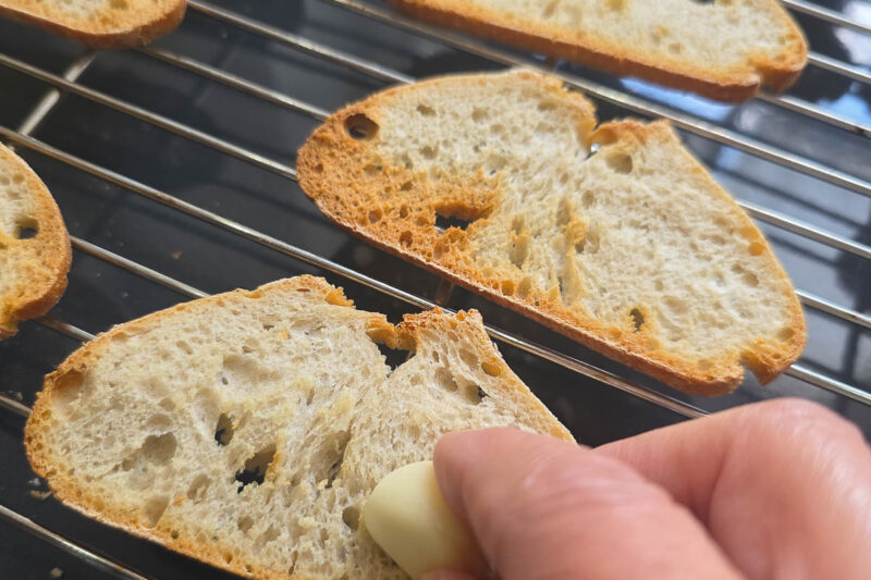 Das brot für den spargelsalat mit erdbeeren wird mit knoblauch eingerieben