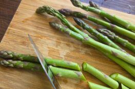 der grüne spargel wird in stücke geschnitten für den spargelsalat mit erdbeeren