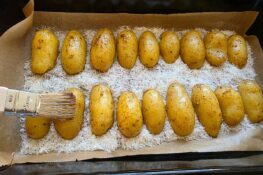 Kartoffeln in der Auflaufform werden mit Öl bepinselt